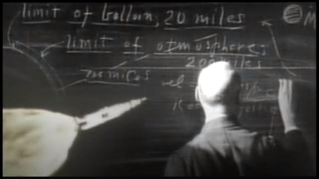 A rocket scientist does math on a chalkboard.